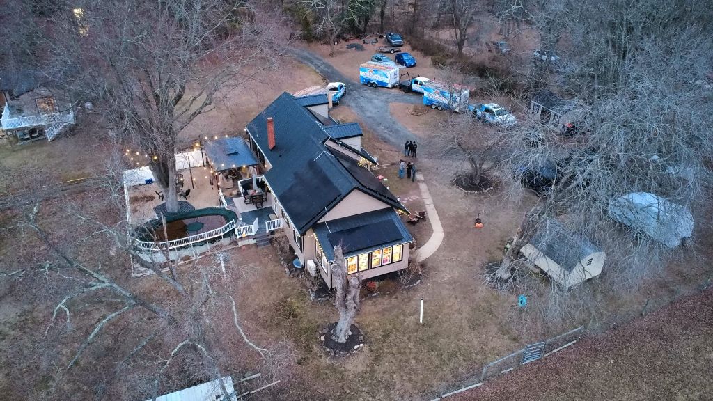 Aerial dusk view of a home with solar panels installed, lights on inside