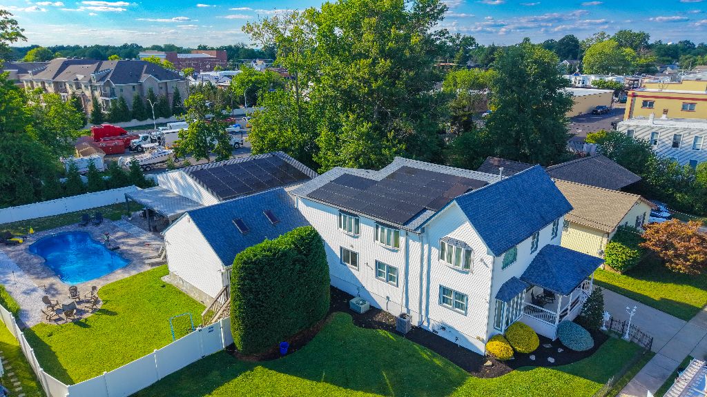 Aerial view of a solar panel array on a home near a downtown area with a backyard pool